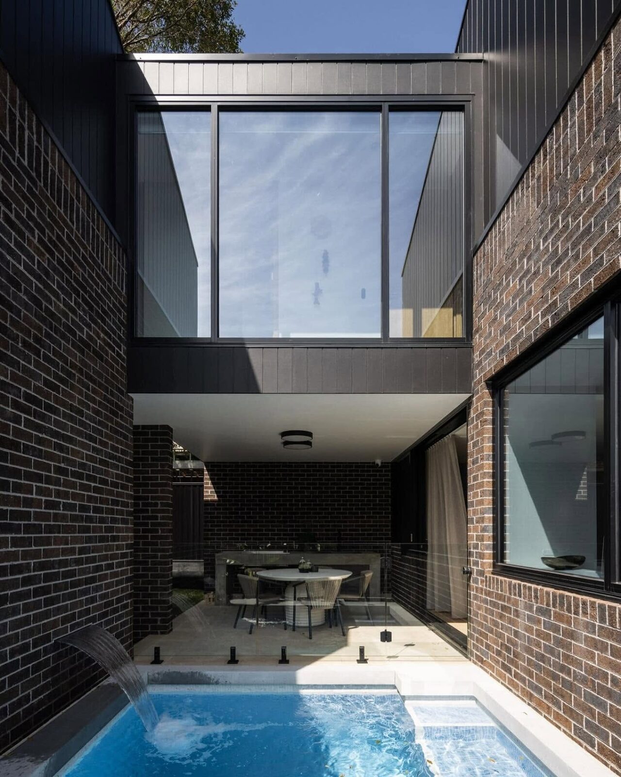Architectural home with black cladding and a brick courtyard pool, painted by Luxe Effects
